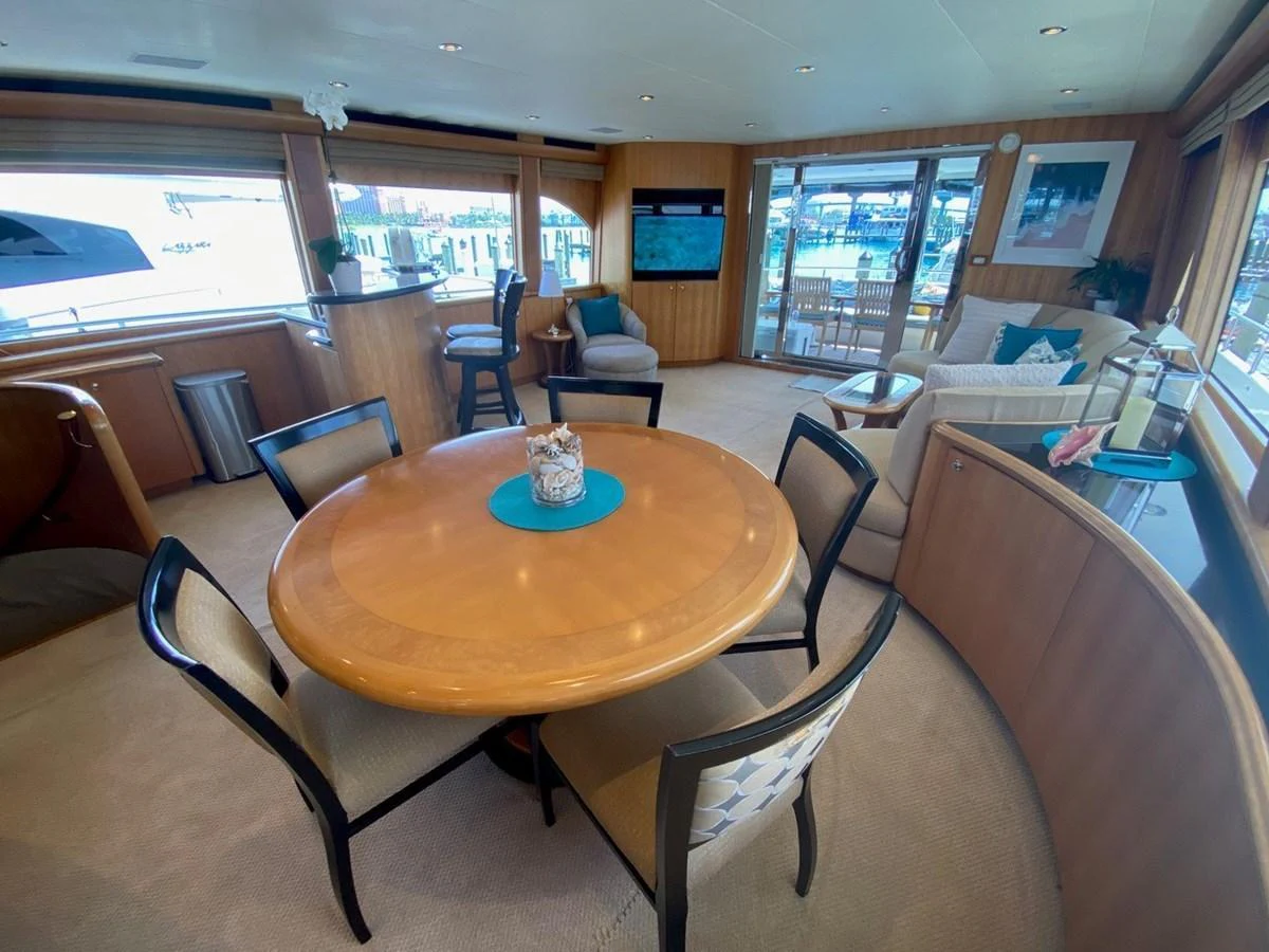 The salon features a cozy dining area with a round table and comfortable seating, complemented by large windows offering scenic views. aboard BREAKAWAY Yacht for Sale