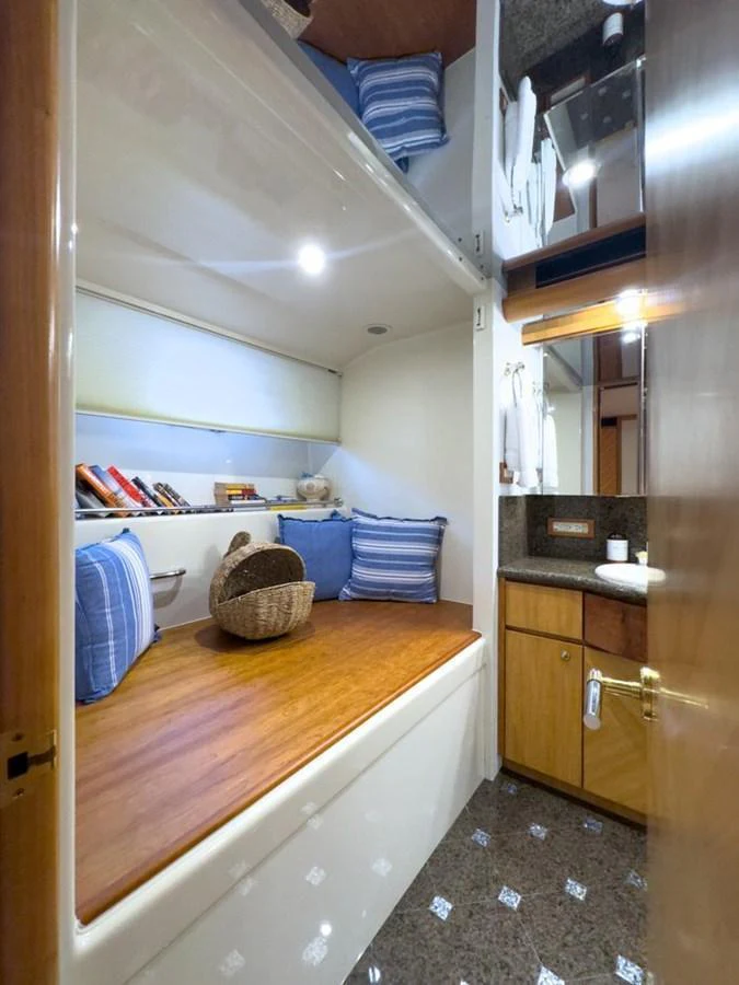 A cozy cabin with wooden accents and blue-striped pillows, featuring a small sink and storage area. aboard BREAKAWAY Yacht for Sale