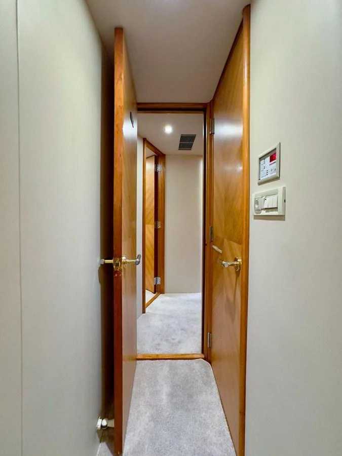A hallway with wooden doors and soft carpeting leads to various rooms inside the yacht. aboard BREAKAWAY Yacht for Sale