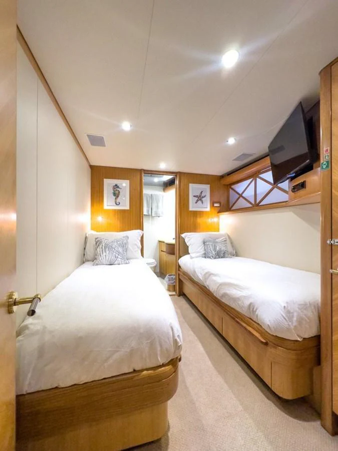 The twin stateroom offers a cozy and inviting space with two single beds and warm wood accents. aboard BREAKAWAY Yacht for Sale