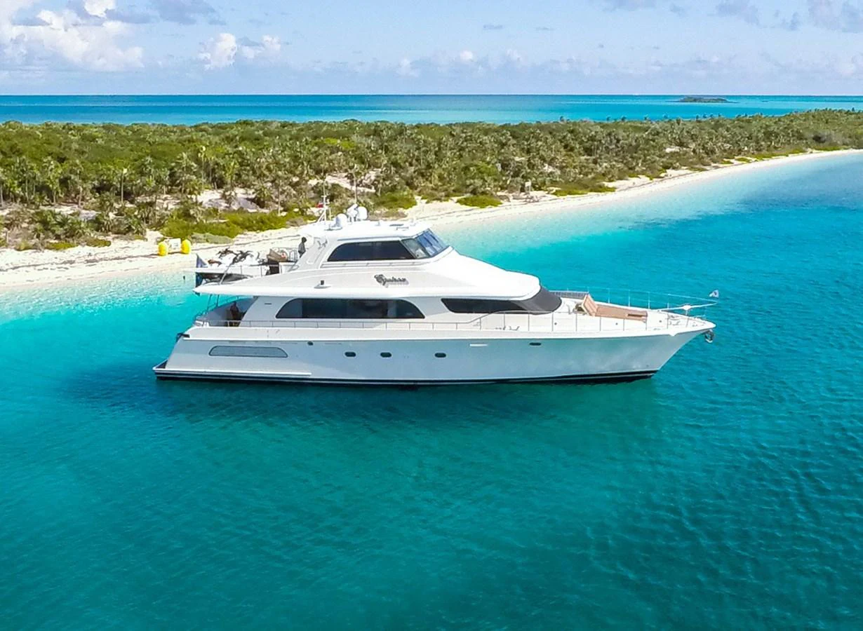 A sleek yacht cruises along a pristine coastline with turquoise waters and lush greenery. aboard BREAKAWAY Yacht for Sale