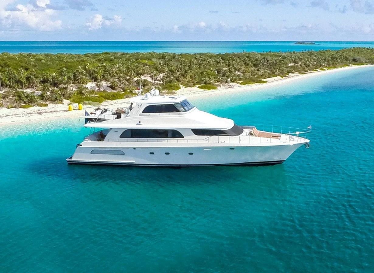 A sleek yacht cruises along a pristine coastline with turquoise waters and lush greenery. aboard BREAKAWAY Yacht for Sale