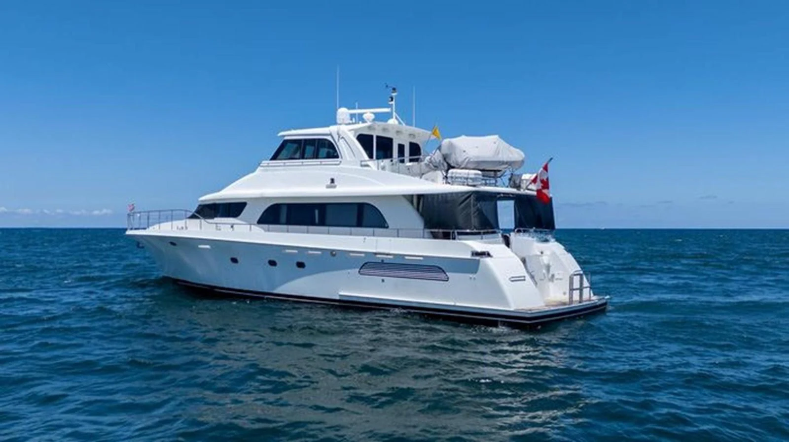A sleek and elegant yacht cruising on calm blue waters under a clear sky. aboard BREAKAWAY Yacht for Sale