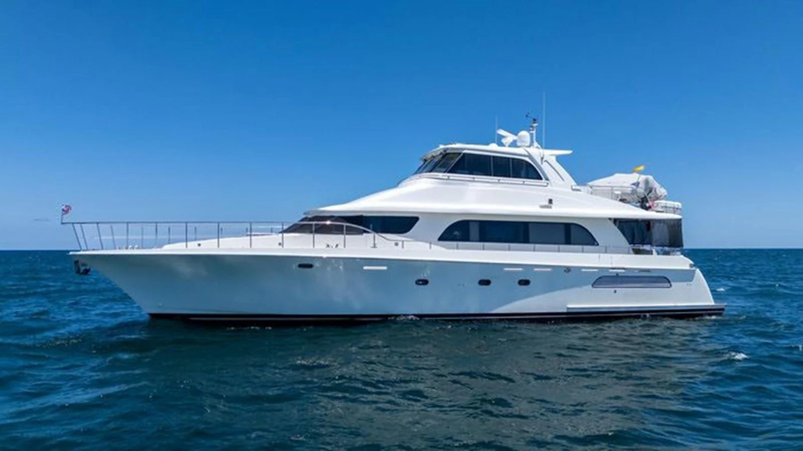 A sleek and elegant yacht cruising on the open sea under a clear blue sky. aboard BREAKAWAY Yacht for Sale