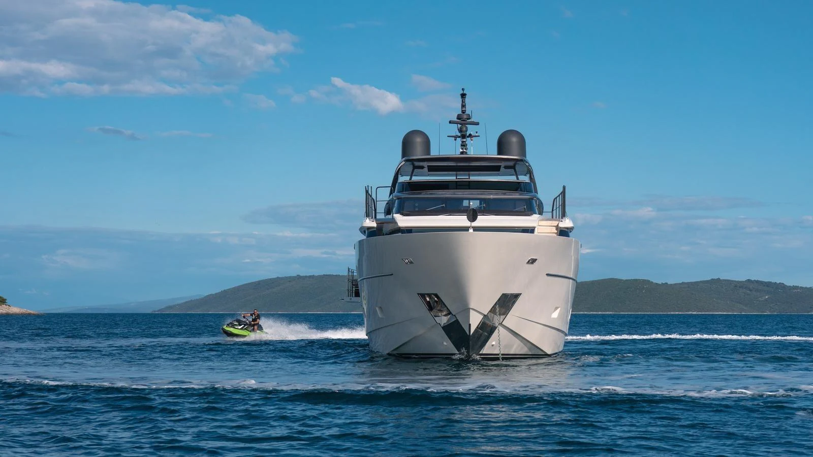 A sleek yacht cruises forward on a calm sea under a clear blue sky. aboard JOURNEY Yacht for Sale