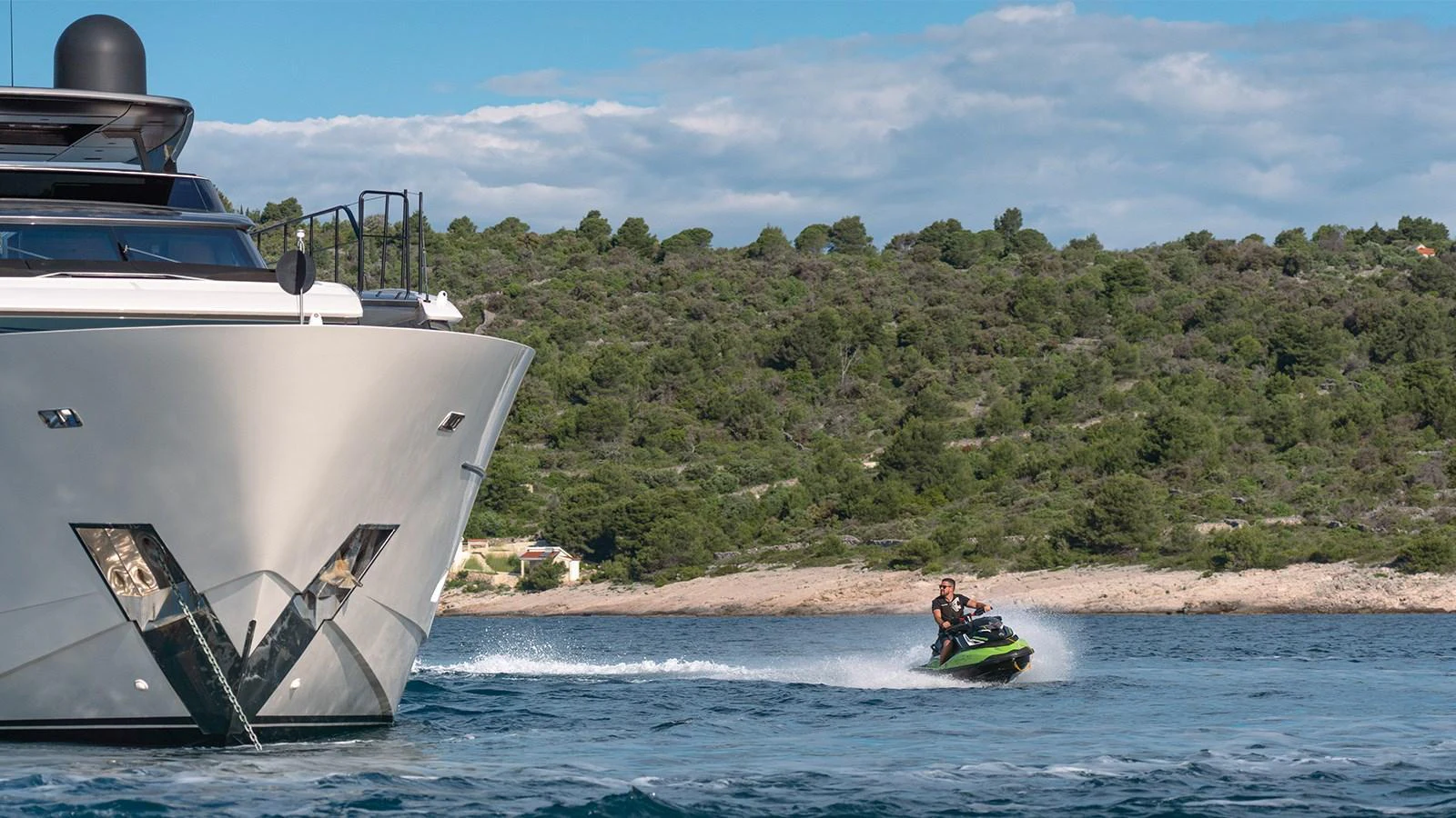 A sleek yacht cruises through calm waters with a jet ski speeding alongside. aboard JOURNEY Yacht for Sale