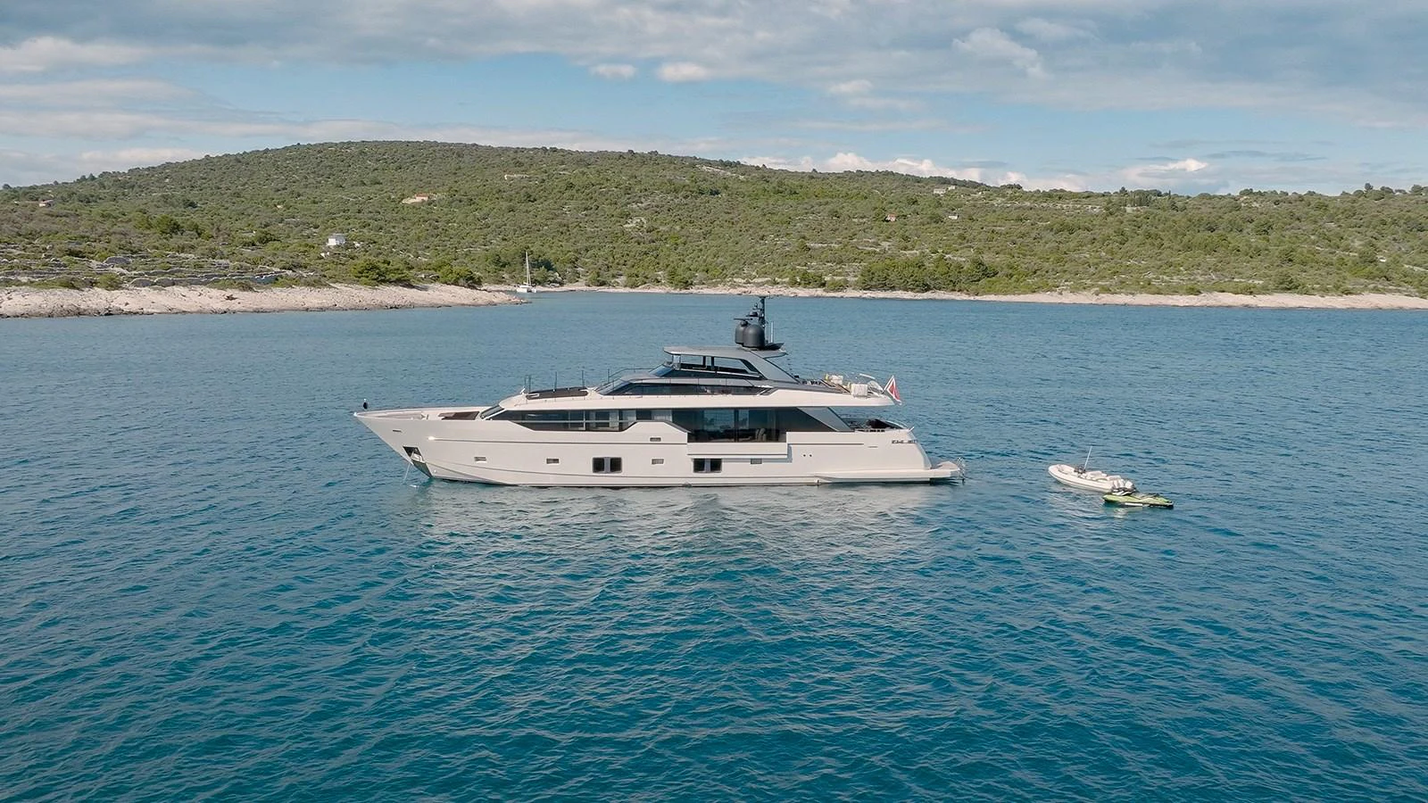 A sleek and modern yacht is anchored in calm waters near a scenic coastline. aboard JOURNEY Yacht for Sale