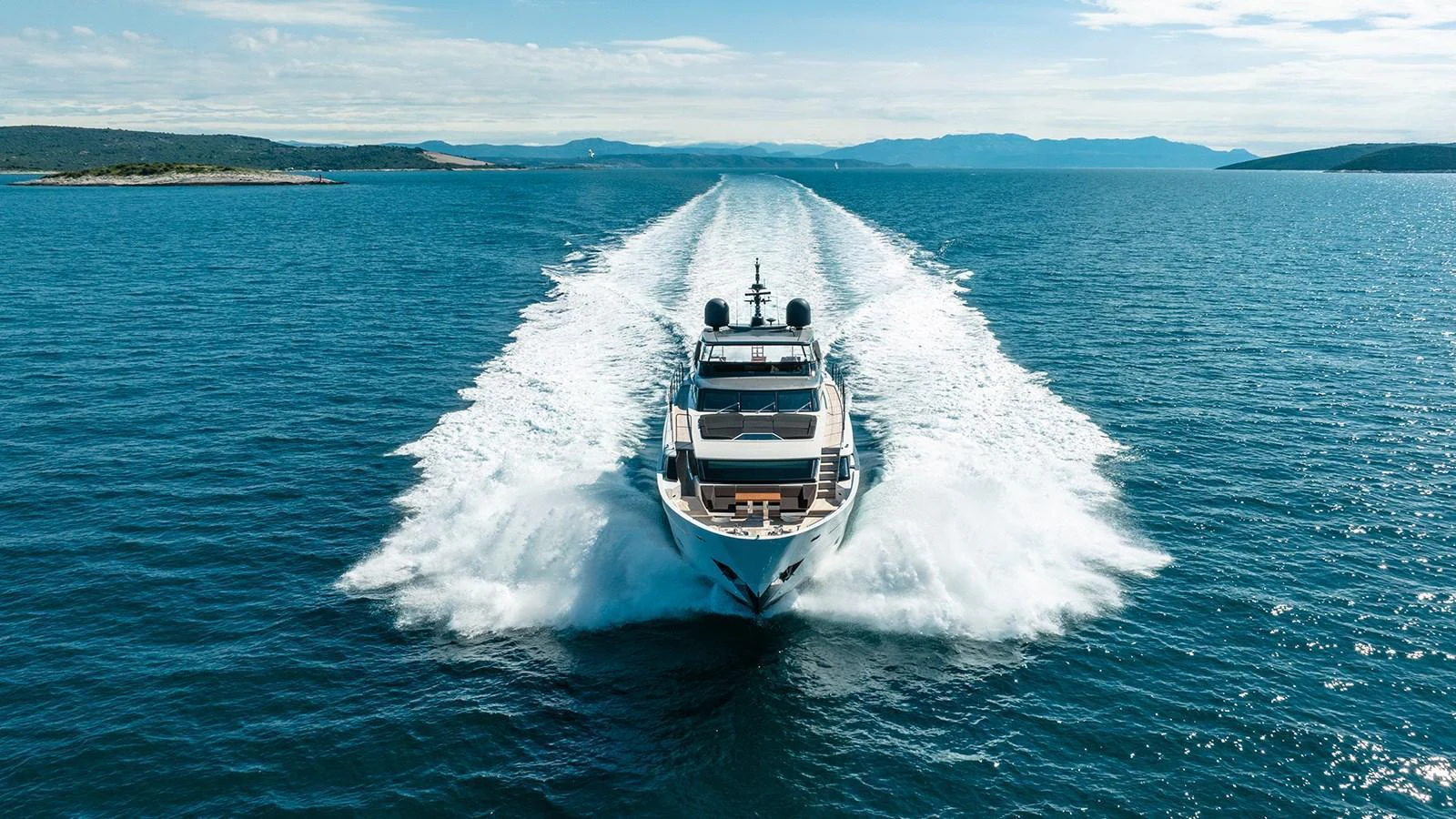 A luxurious yacht cruises through clear blue waters, leaving a trail of white wake behind. aboard JOURNEY Yacht for Sale