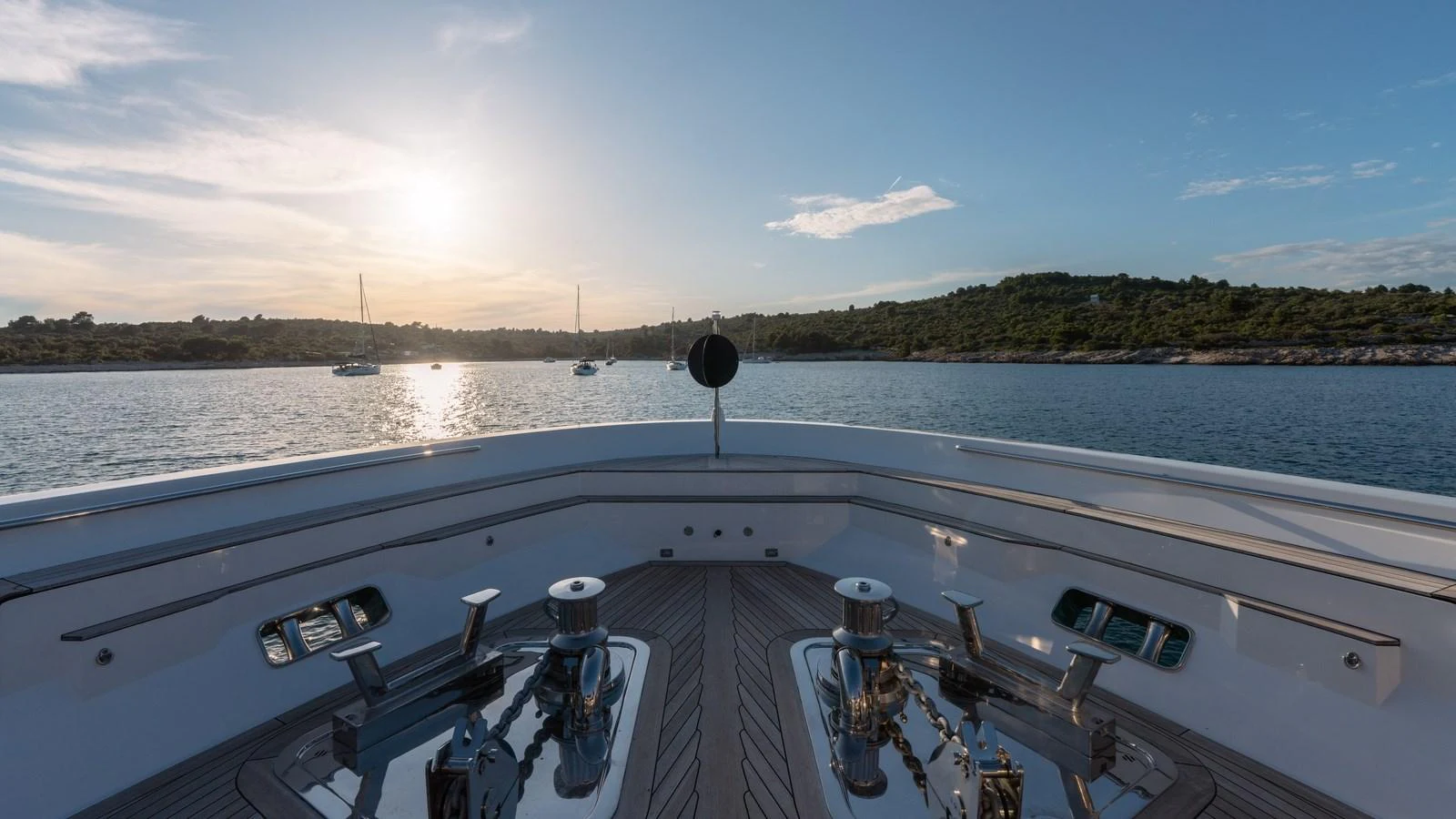 The foredeck of the yacht offers a serene view of the water and distant shoreline at sunset. aboard JOURNEY Yacht for Sale