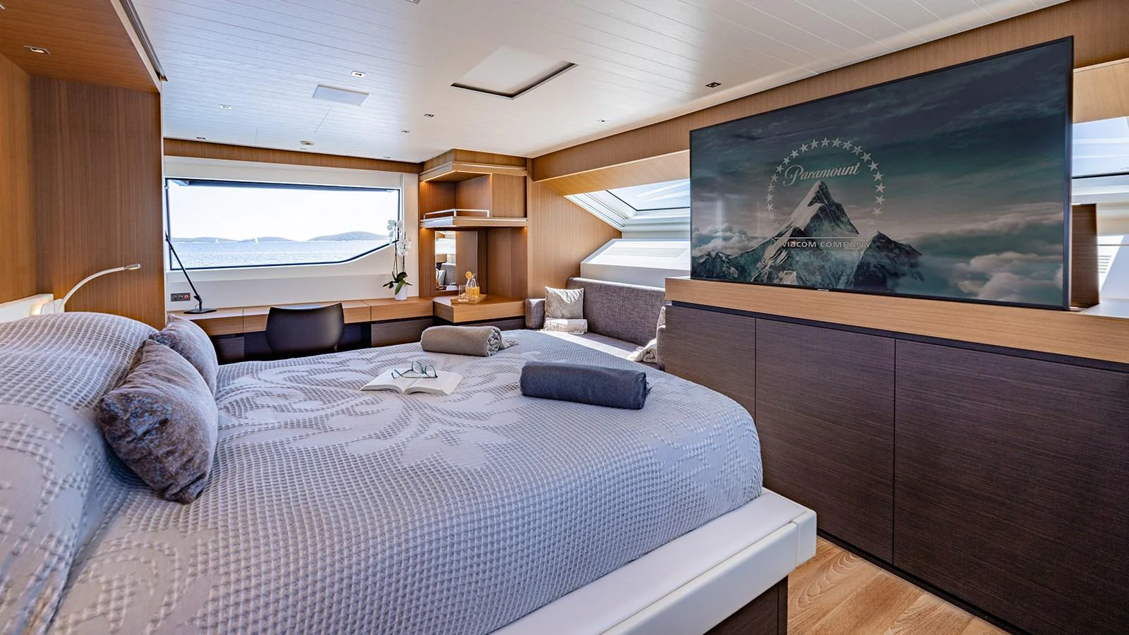 The master stateroom features a spacious bed, large windows, and a flat-screen TV, offering luxurious comfort and stunning views. aboard JOURNEY Yacht for Sale