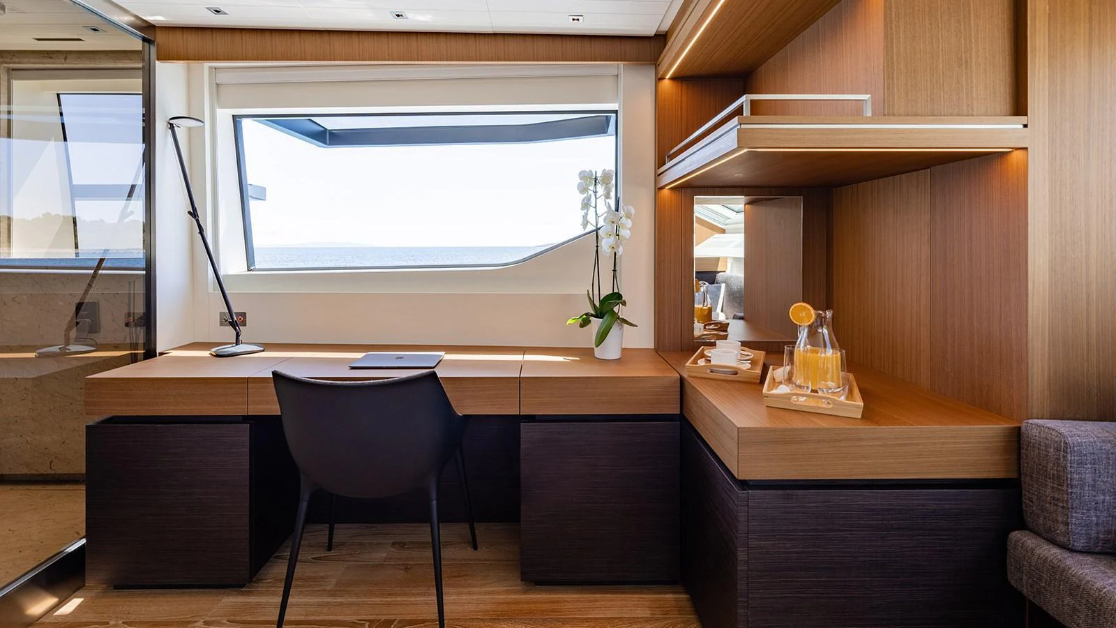 The yacht's office space features a sleek desk with a view of the ocean through a large window. aboard JOURNEY Yacht for Sale