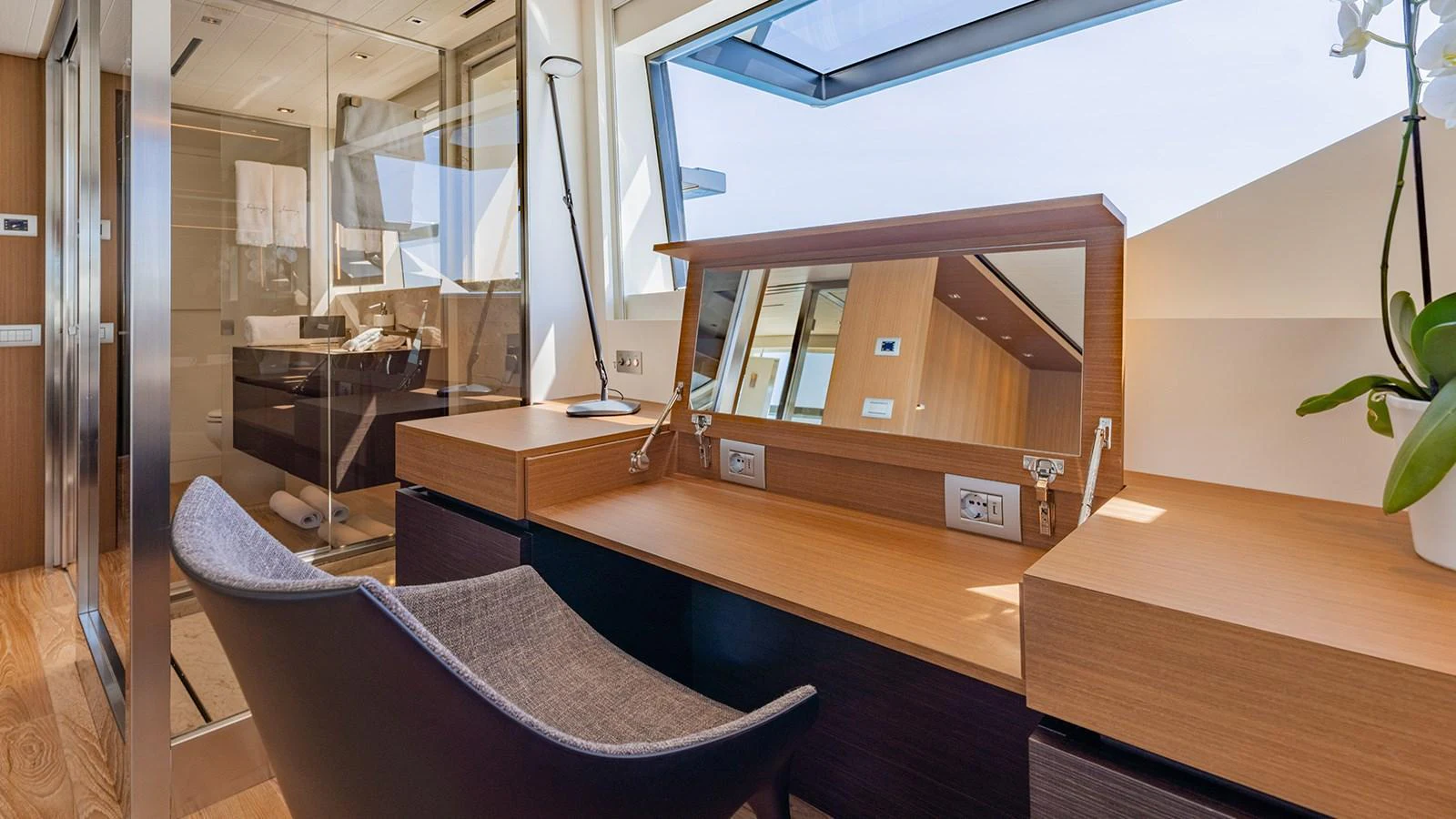 This image showcases a luxurious vanity area with modern furnishings and ample natural light. aboard JOURNEY Yacht for Sale