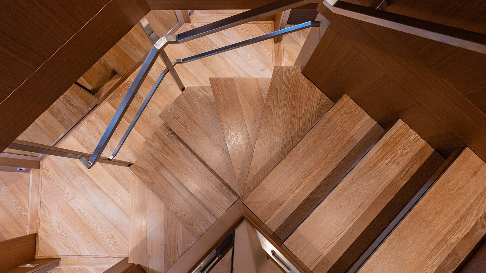 A beautifully crafted wooden staircase with sleek metal railings. aboard JOURNEY Yacht for Sale