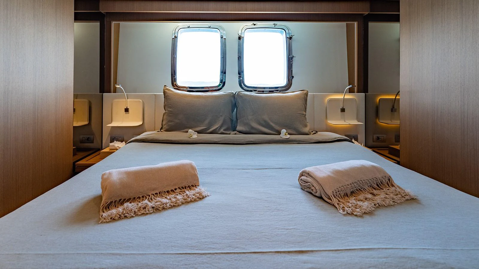 A cozy stateroom featuring a comfortable bed with soft linens and natural light from the portholes. aboard JOURNEY Yacht for Sale