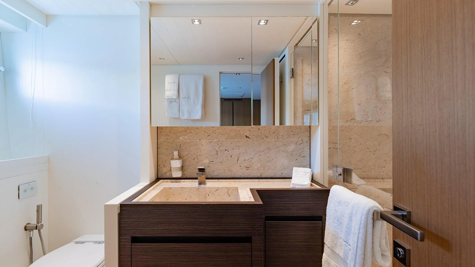 A modern yacht bathroom featuring sleek wooden cabinetry and a spacious shower area. aboard JOURNEY Yacht for Sale