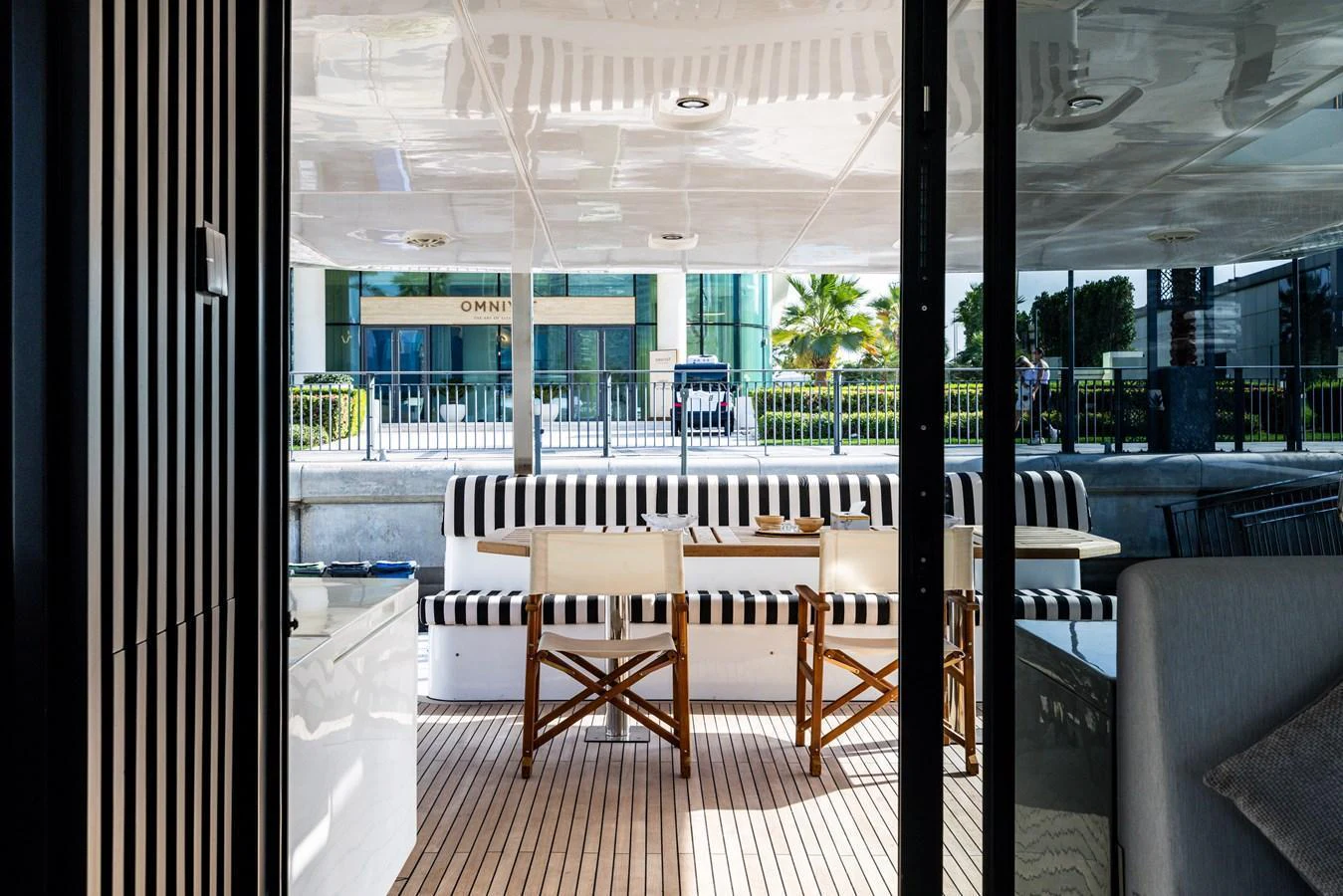 The aft deck features a stylish seating area with striped cushions and wooden chairs, perfect for relaxing and socializing. aboard AL SULTAN Yacht for Sale