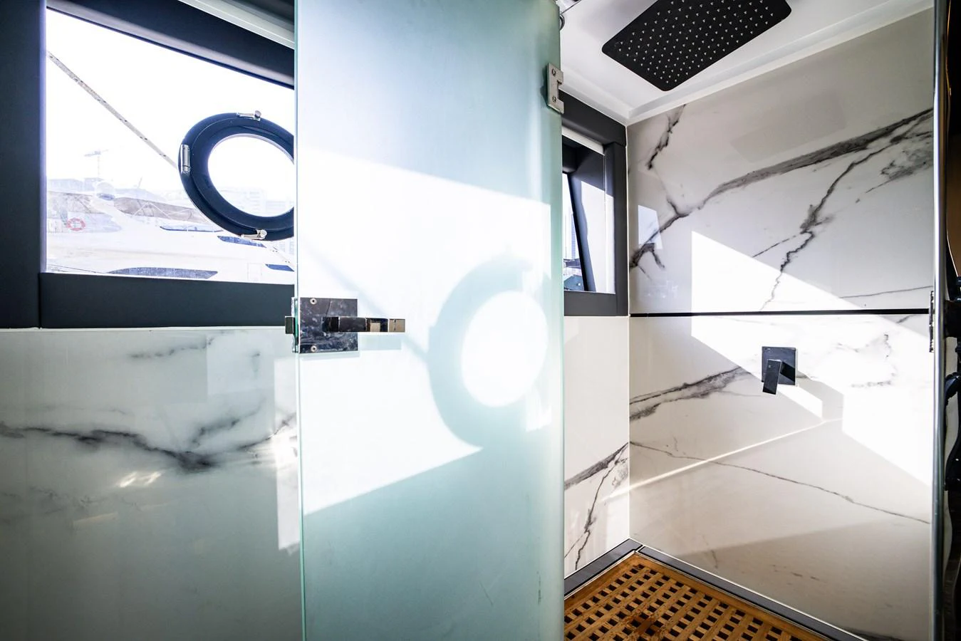 The yacht's bathroom features a modern design with marble walls and a frosted glass door. aboard AL SULTAN Yacht for Sale