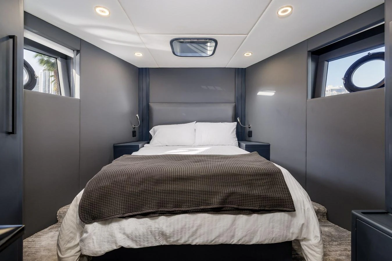 A cozy stateroom featuring a comfortable bed with modern lighting and ample natural light from side windows. aboard AL SULTAN Yacht for Sale