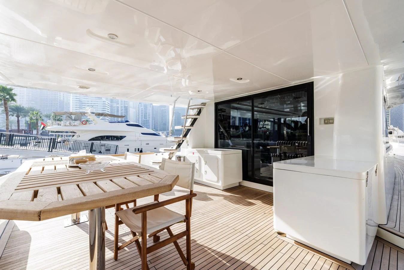 The aft deck features a spacious seating area with a wooden table and chairs, perfect for outdoor dining and relaxation. aboard AL SULTAN Yacht for Sale