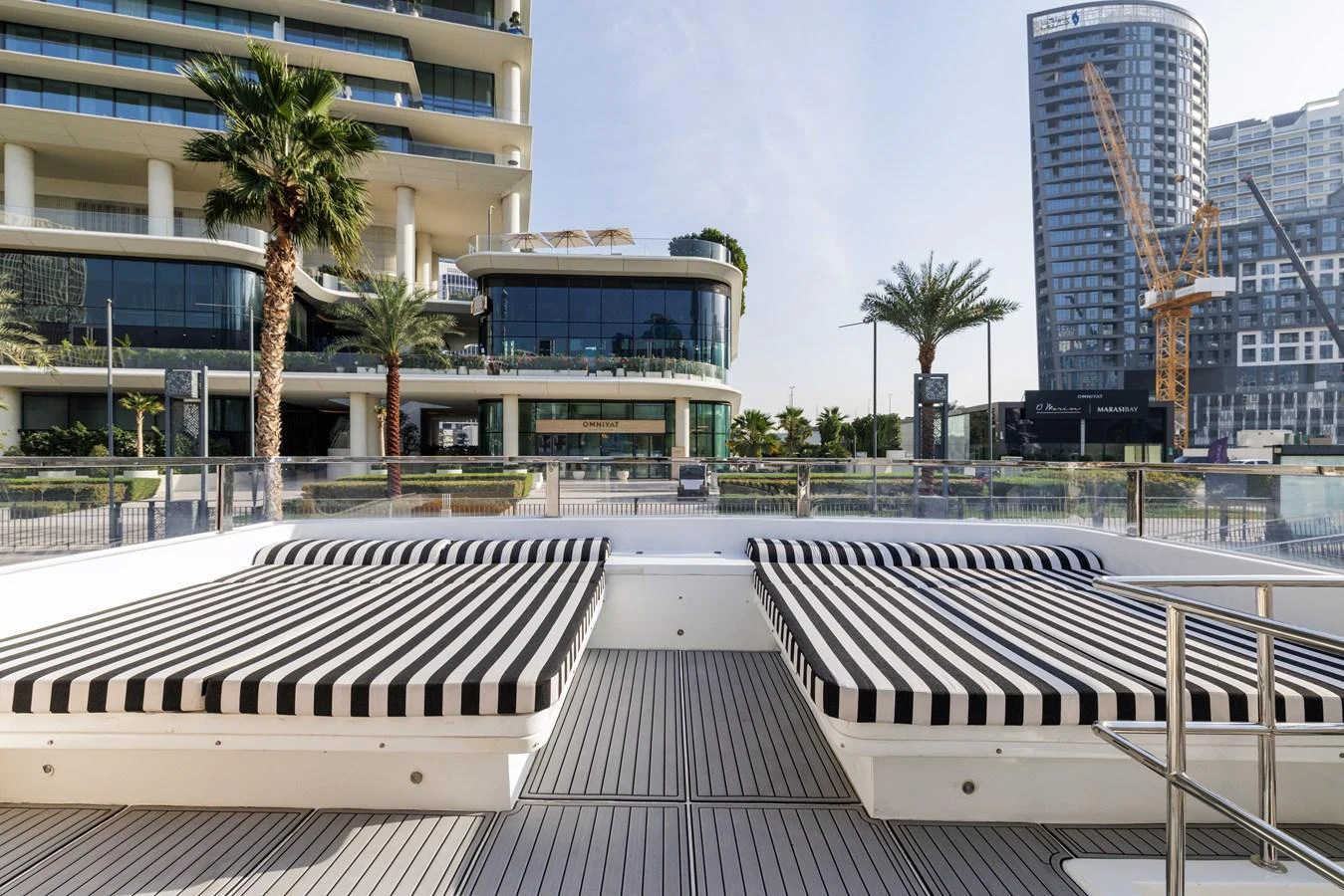 The sundeck features luxurious striped sunbeds with a modern urban backdrop. aboard AL SULTAN Yacht for Sale