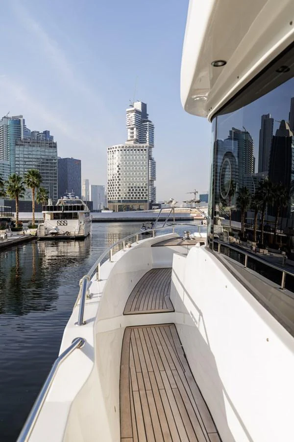 The yacht's side deck offers a sleek walkway with a view of the marina and city skyline. aboard AL SULTAN Yacht for Sale