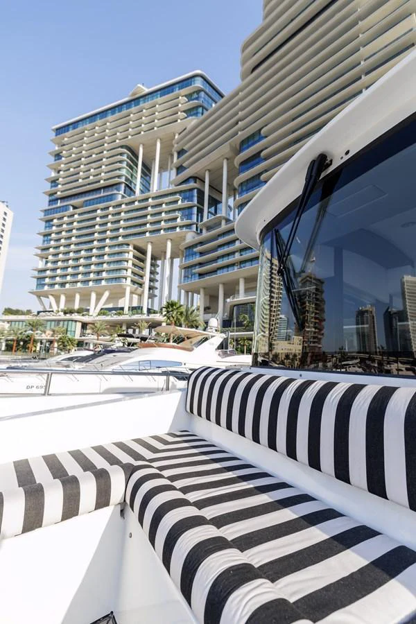 The yacht is docked in a modern marina with striking architectural buildings in the background. aboard AL SULTAN Yacht for Sale