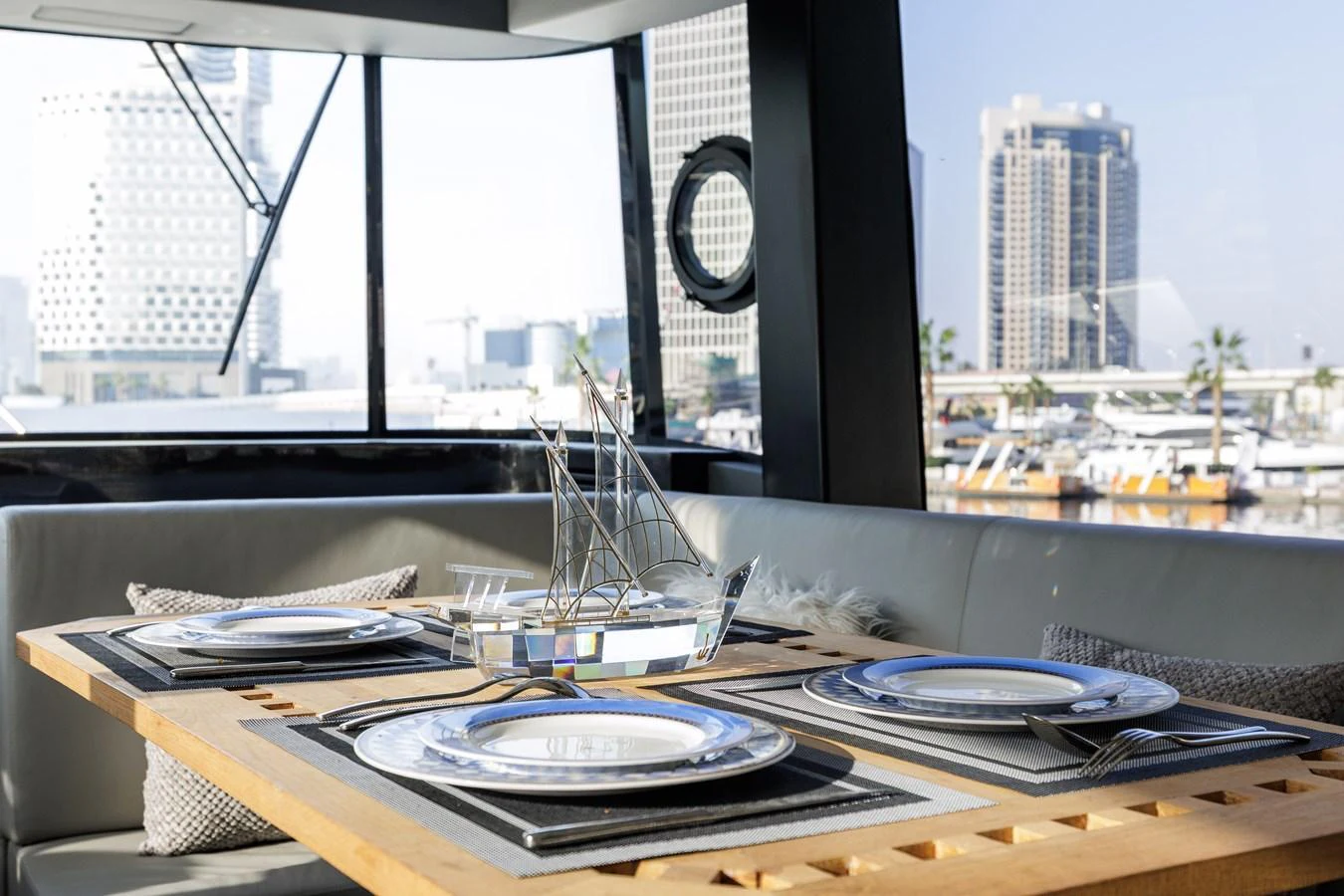 A stylish dining area with a modern table set for four, offering a view of the marina through large windows. aboard AL SULTAN Yacht for Sale