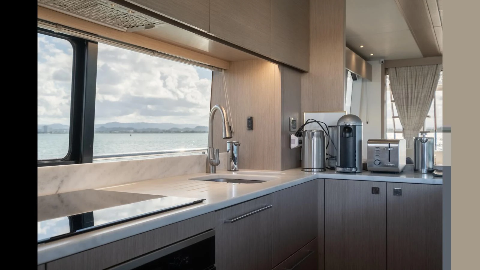 The yacht's galley features modern appliances and a sleek design with a scenic view through the window. aboard ONLY 1100 HRS! Yacht for Sale