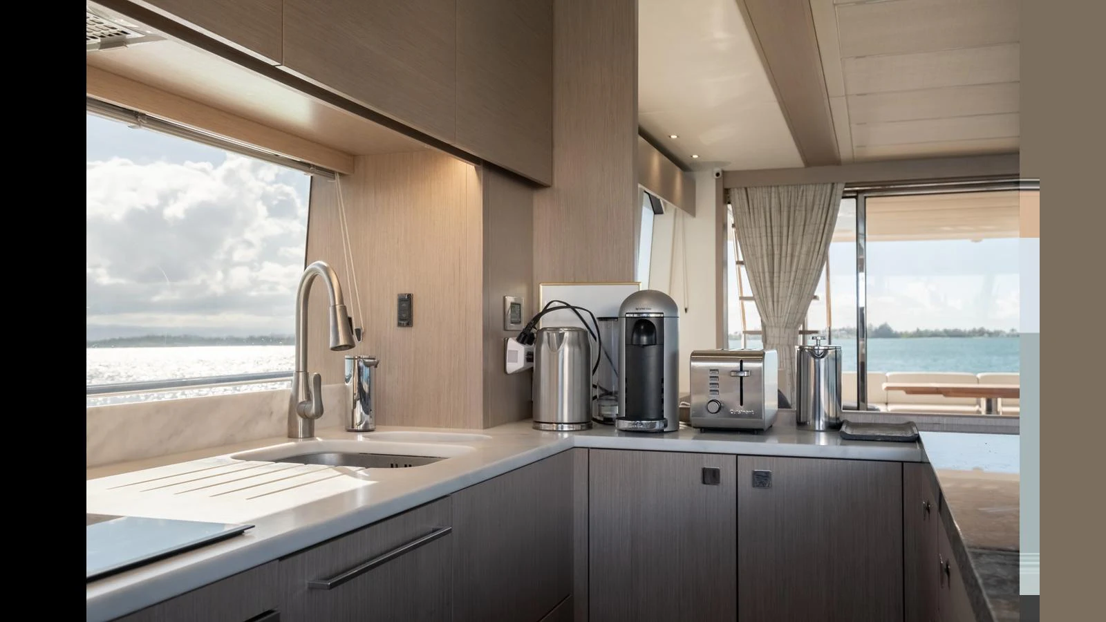 The yacht's galley is modern and well-equipped, featuring sleek appliances and ample counter space with a view of the water. aboard ONLY 1100 HRS! Yacht for Sale