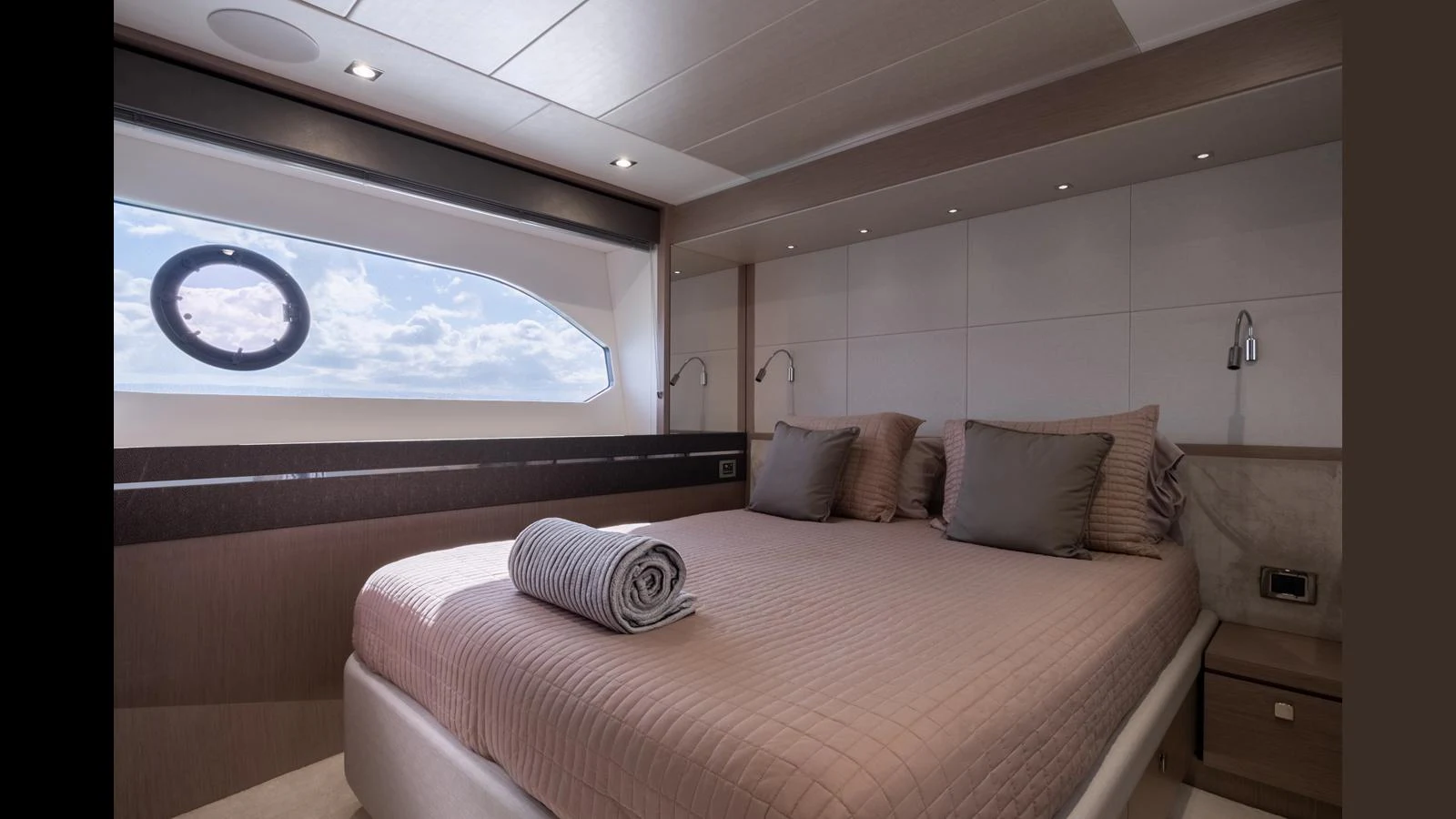 A luxurious stateroom featuring a large bed with plush pillows and a rolled towel, illuminated by natural light from a porthole window. aboard ONLY 1100 HRS! Yacht for Sale
