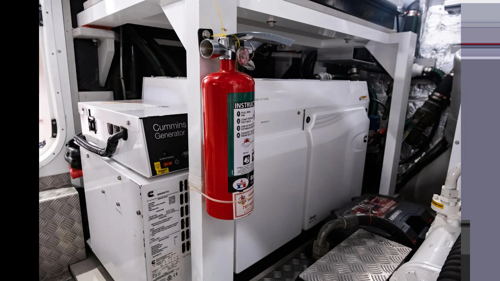 The image showcases the engine room with a Cummins generator and a fire extinguisher. aboard ONLY 1100 HRS! Yacht for Sale