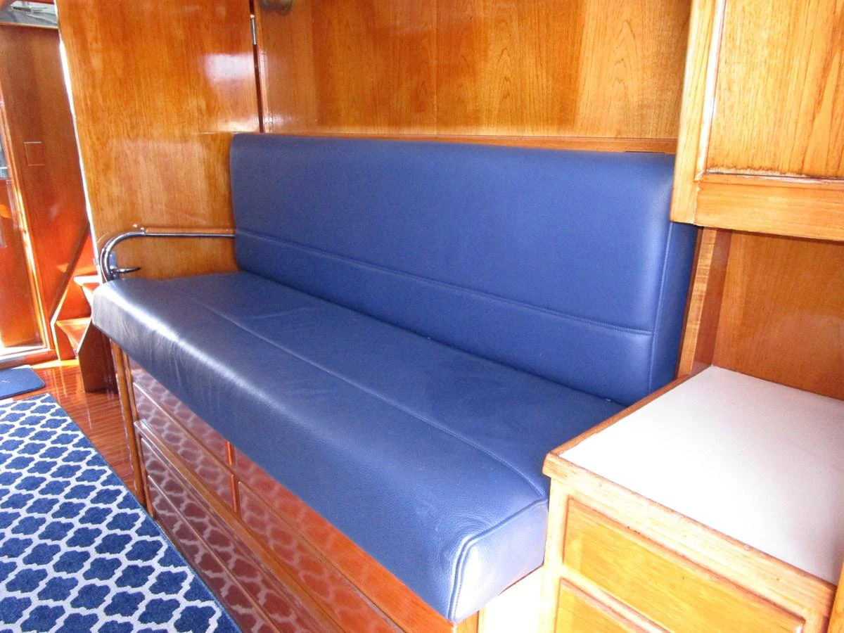 The yacht's interior features a comfortable seating area with blue upholstery and wooden cabinetry. aboard SHEPSL X Yacht for Sale