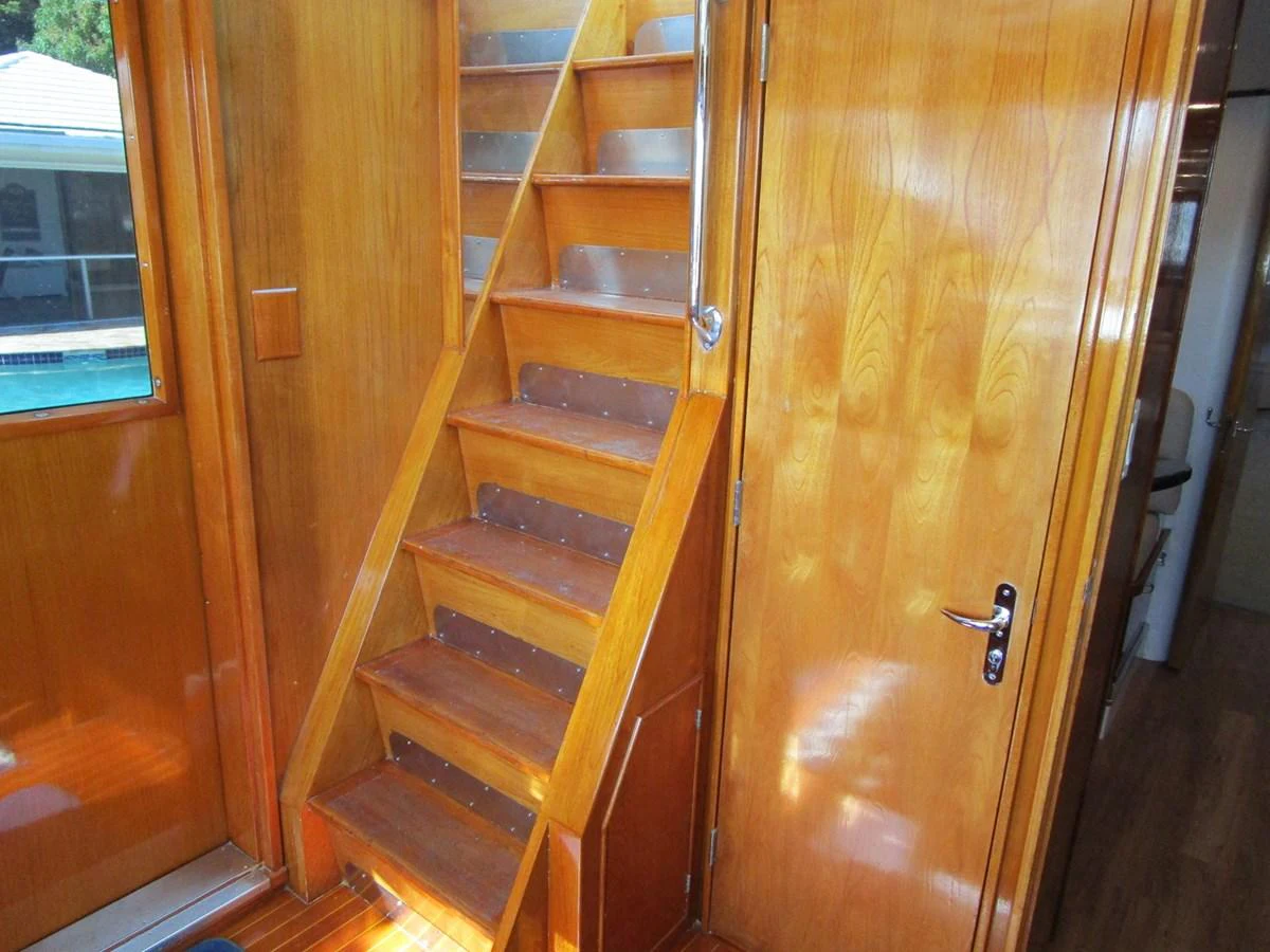 The image showcases a polished wooden staircase inside the yacht, leading to another level. aboard SHEPSL X Yacht for Sale