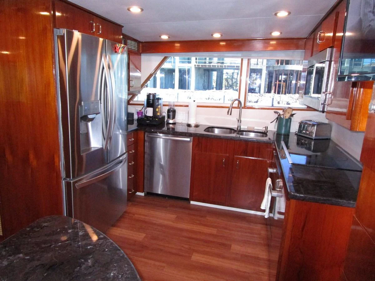 The yacht's galley features modern stainless steel appliances and rich wooden cabinetry, creating a warm and functional space. aboard SHEPSL X Yacht for Sale
