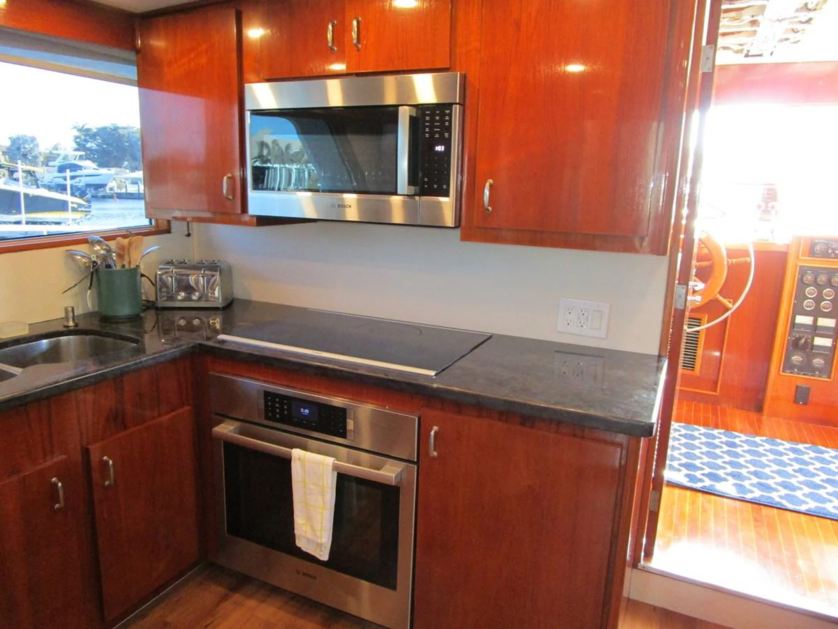 The yacht's galley features modern appliances and rich wood cabinetry, creating a warm and functional space. aboard SHEPSL X Yacht for Sale