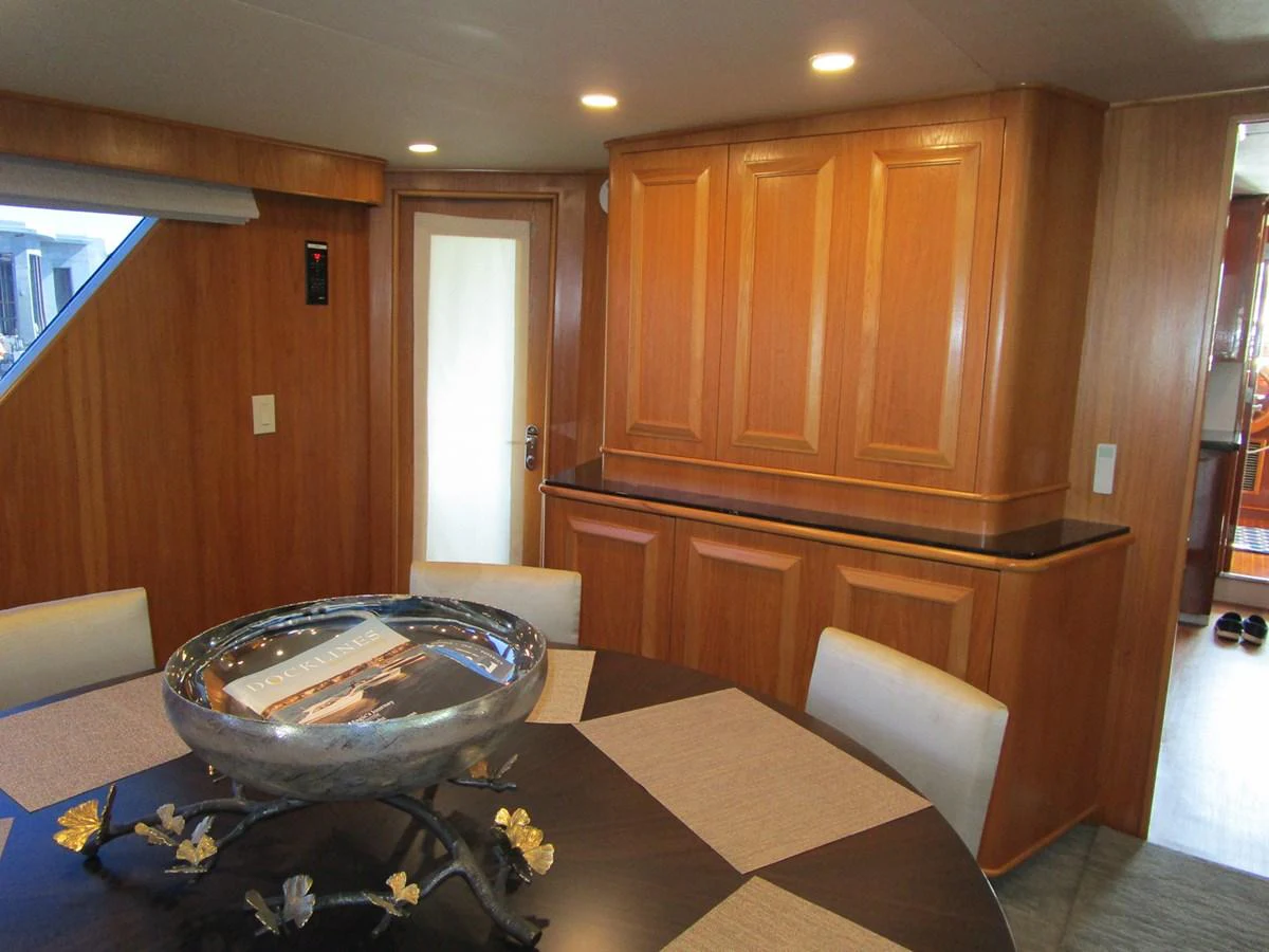 The yacht's dining area features elegant wood cabinetry and a stylish round table. aboard SHEPSL X Yacht for Sale