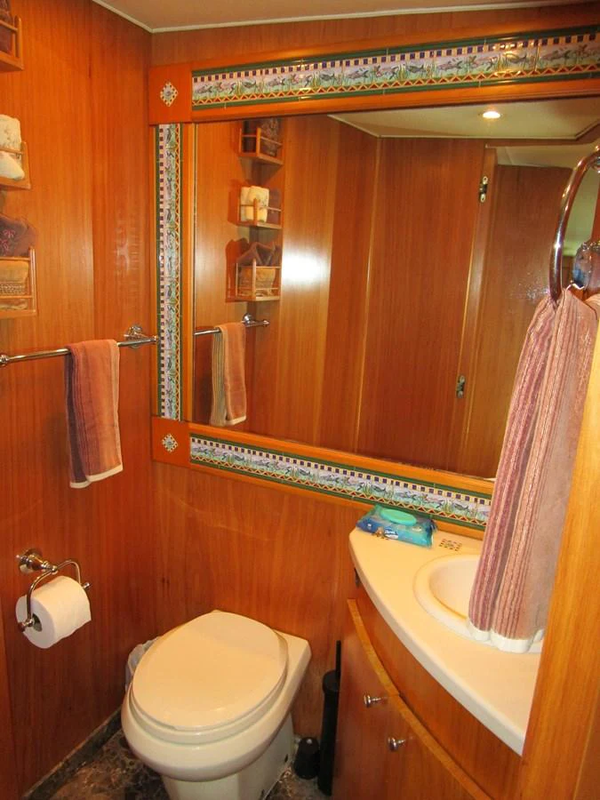 The yacht's bathroom features warm wood paneling and a large mirror, creating a cozy and inviting space. aboard SHEPSL X Yacht for Sale