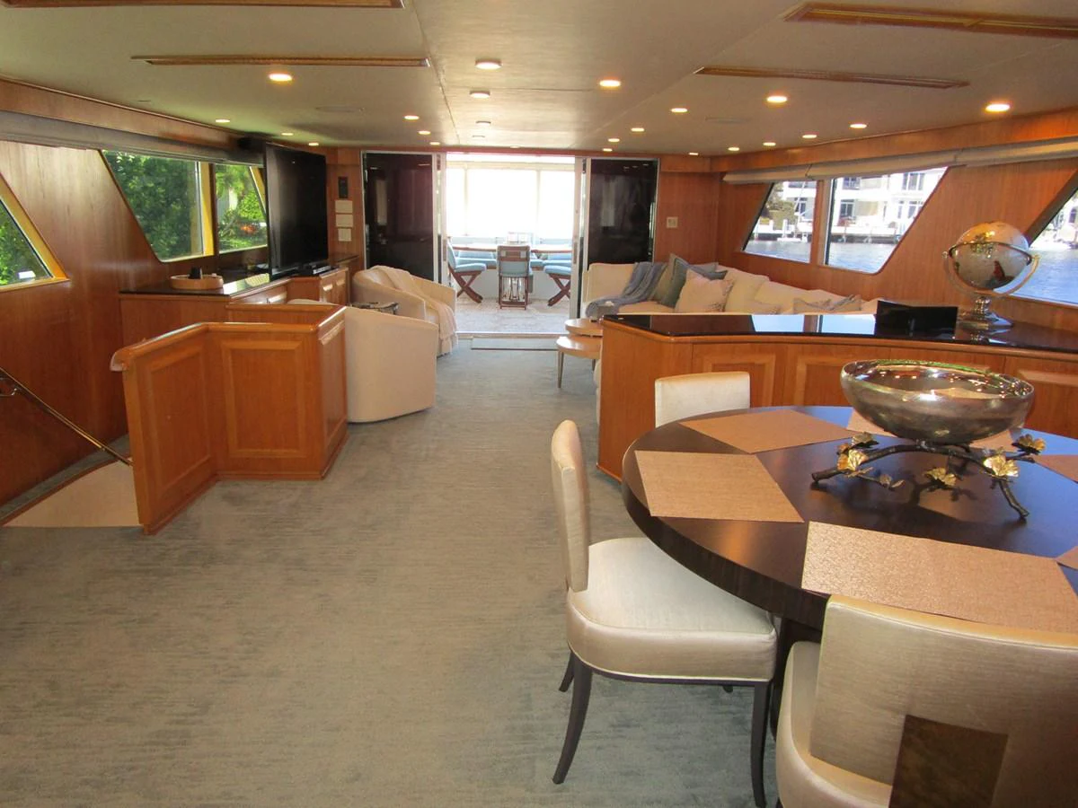 The salon features elegant furnishings with ample seating and a dining area, bathed in natural light from large windows. aboard SHEPSL X Yacht for Sale