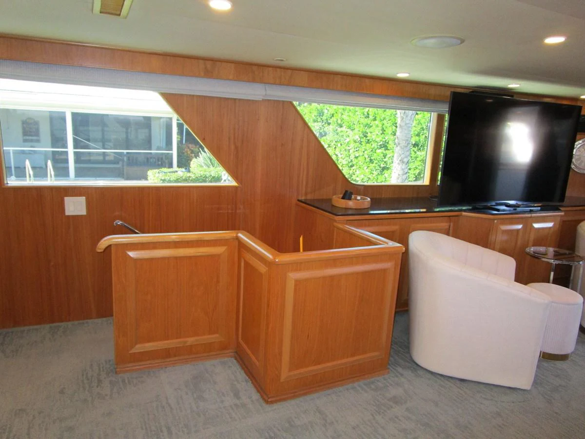 The yacht's interior features a cozy seating area with a large television and wooden paneling. aboard SHEPSL X Yacht for Sale