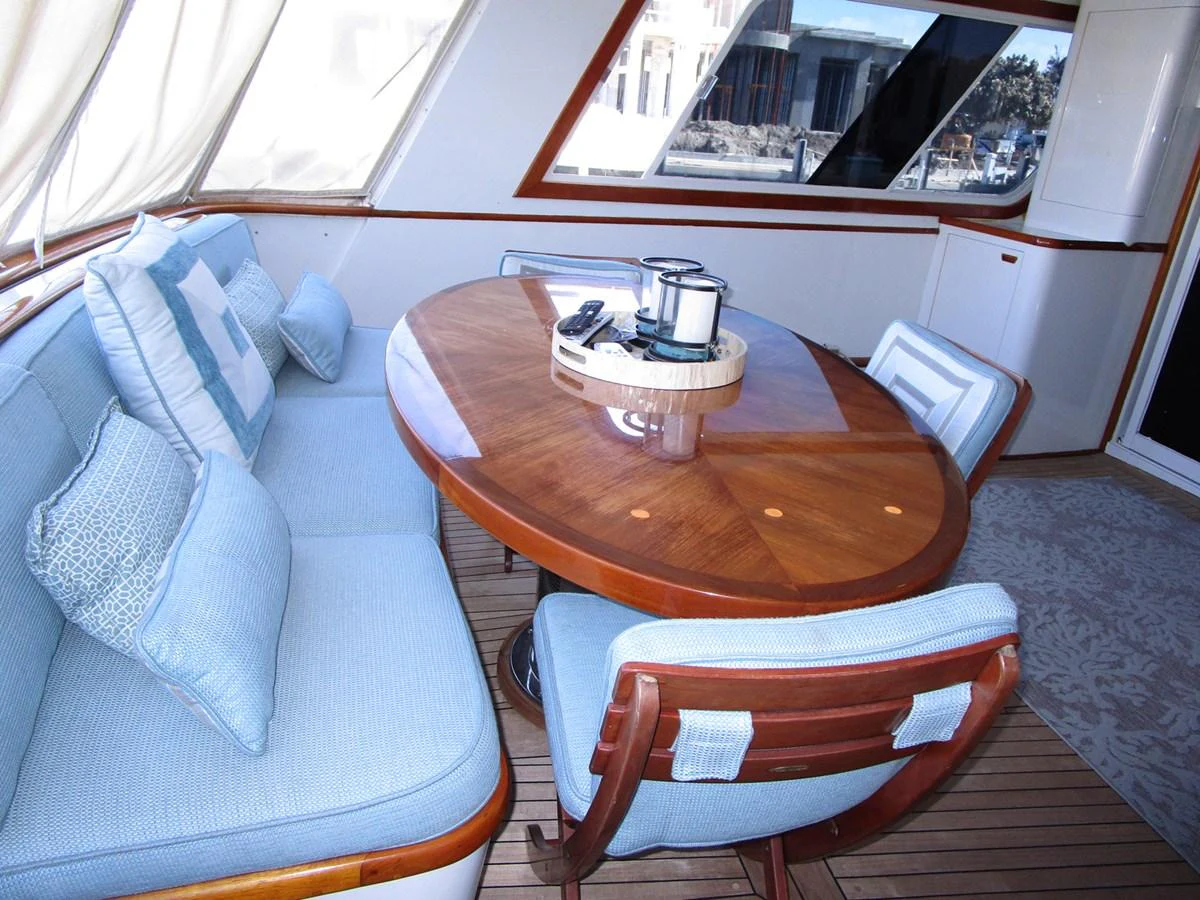 The yacht's dining area features a round wooden table surrounded by comfortable cushioned seating, perfect for intimate meals. aboard SHEPSL X Yacht for Sale