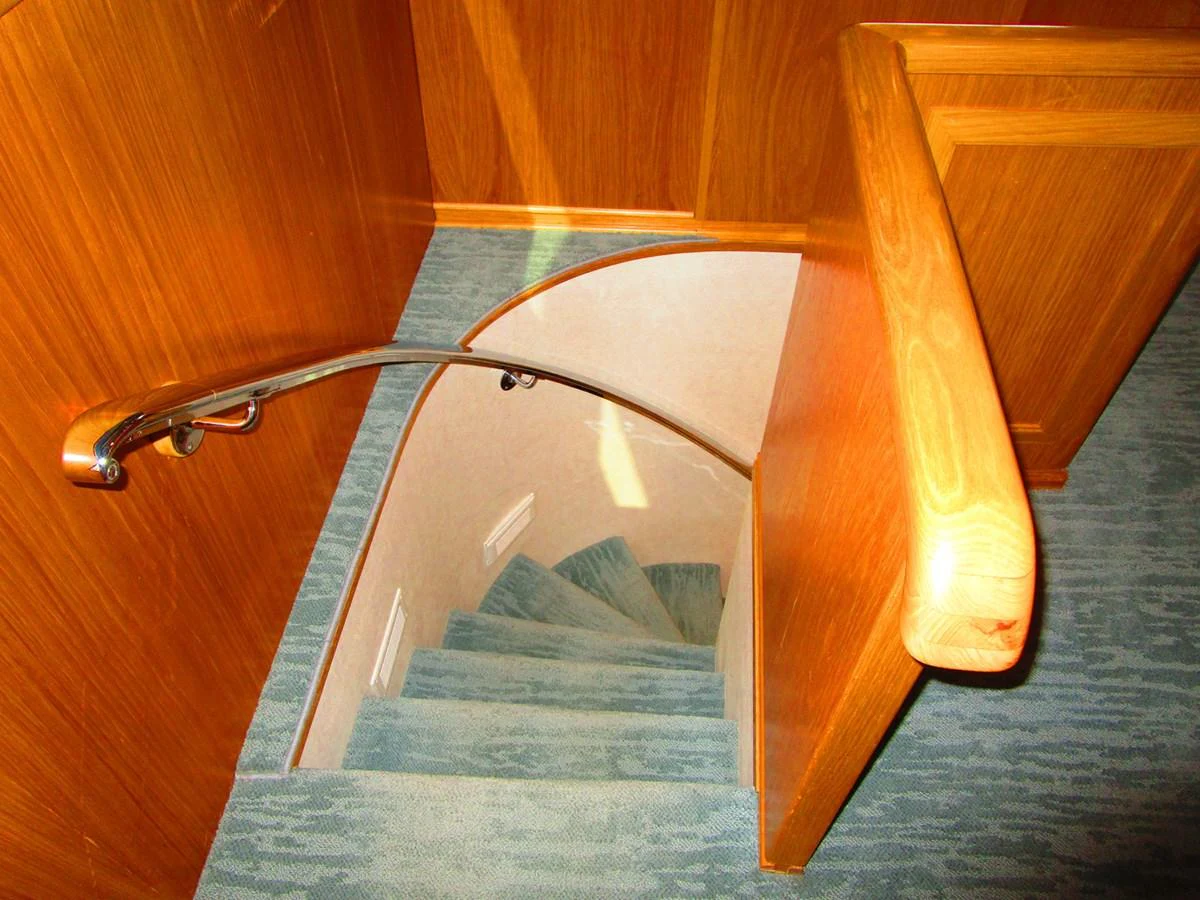 A well-crafted wooden staircase leads to the lower deck of the yacht. aboard SHEPSL X Yacht for Sale