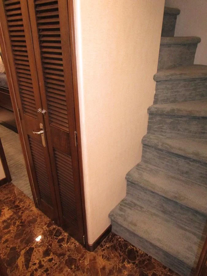 A cozy interior stairway with carpeted steps and a wooden closet door. aboard SHEPSL X Yacht for Sale