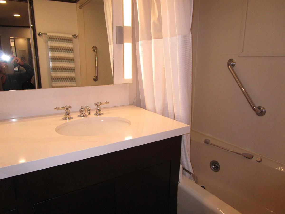 The yacht's bathroom features a sleek vanity and a bathtub with a shower curtain. aboard SHEPSL X Yacht for Sale