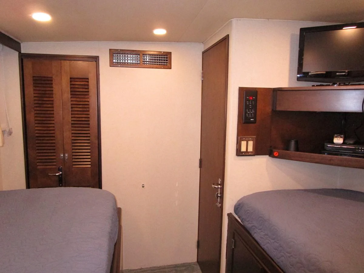 This cozy cabin features twin beds, a wall-mounted TV, and ample storage space. aboard SHEPSL X Yacht for Sale