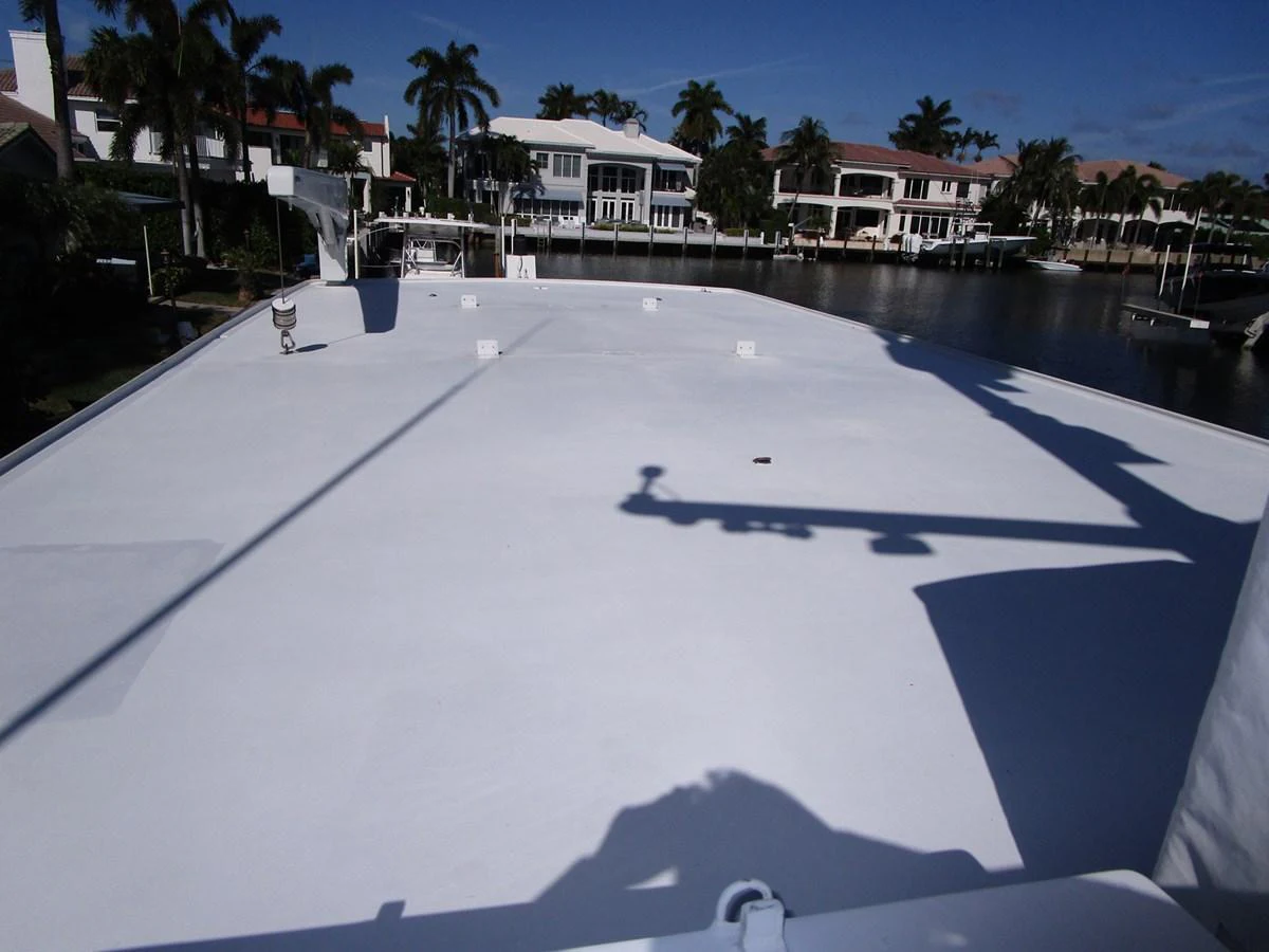 The image shows the top deck of a yacht docked in a marina with waterfront homes in the background. aboard SHEPSL X Yacht for Sale