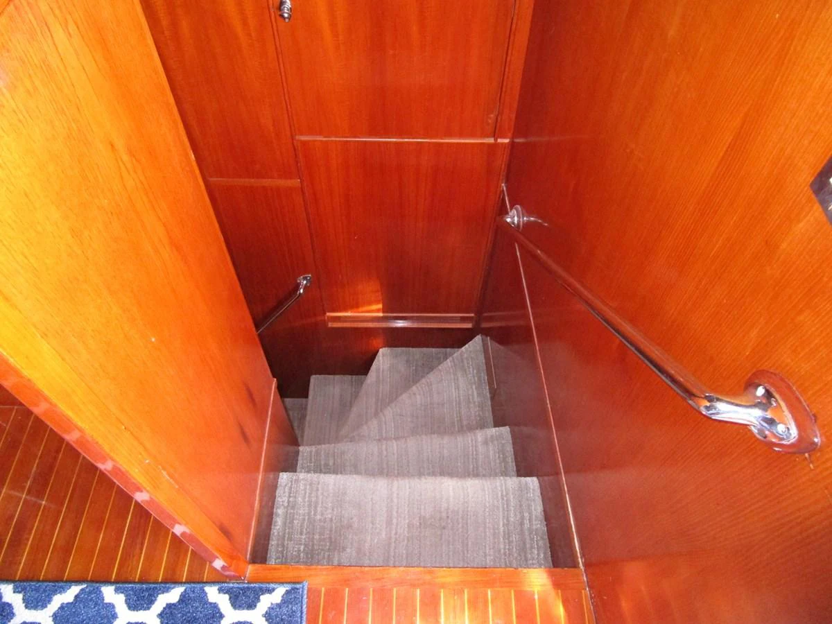 A polished wooden staircase with carpeted steps leads to a lower deck. aboard SHEPSL X Yacht for Sale
