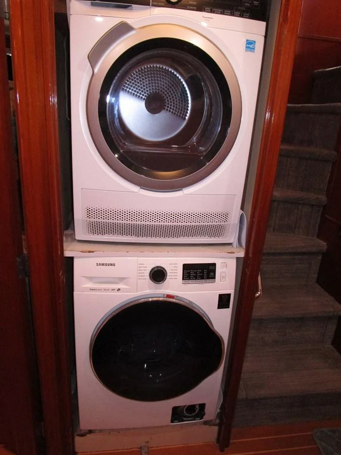 The yacht features a convenient laundry area with a stacked washer and dryer. aboard SHEPSL X Yacht for Sale