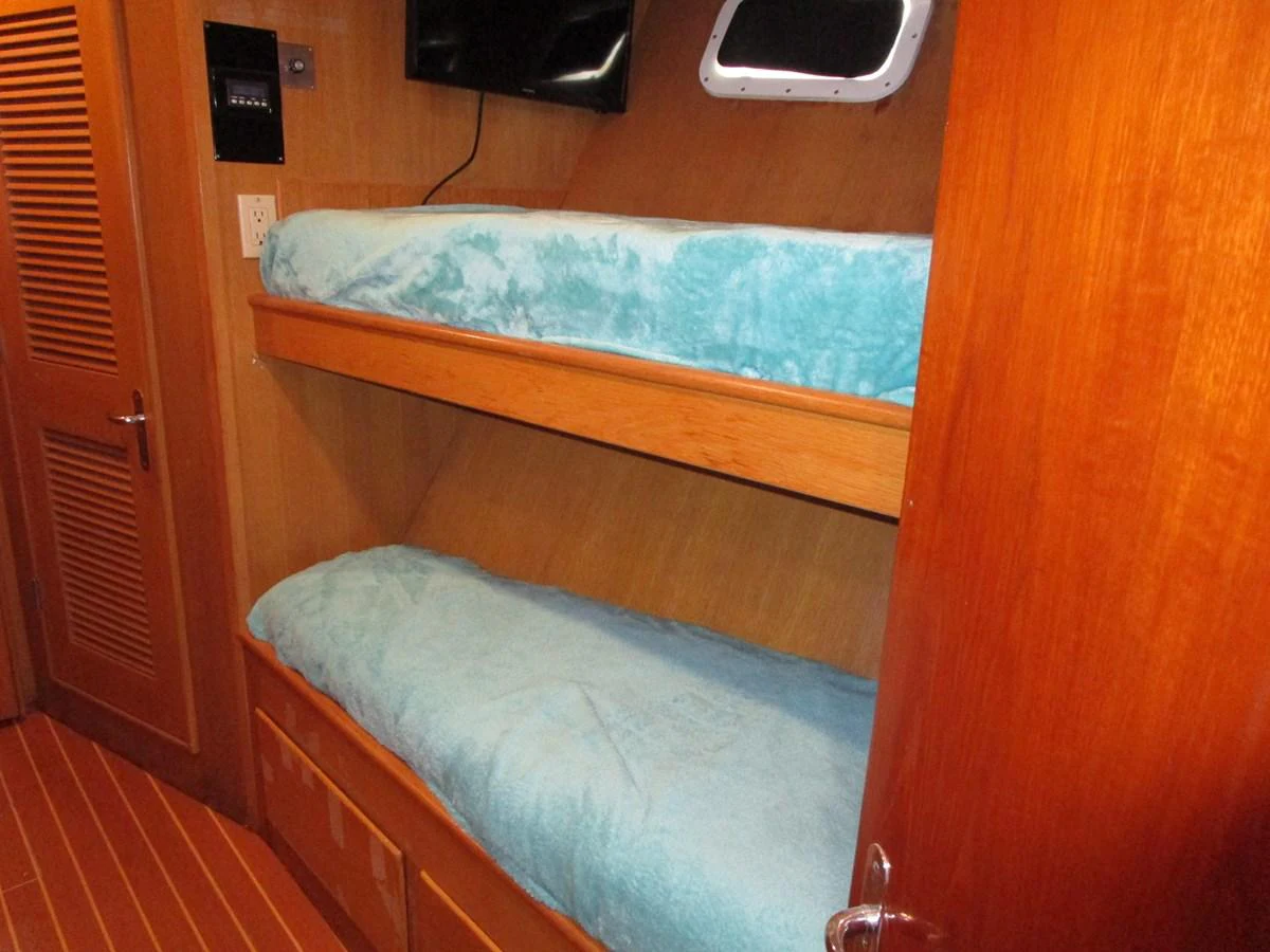 The cozy bunk room features wooden paneling and comfortable bedding. aboard SHEPSL X Yacht for Sale