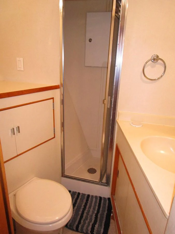 A compact and functional yacht bathroom with a shower, toilet, and sink. aboard SHEPSL X Yacht for Sale