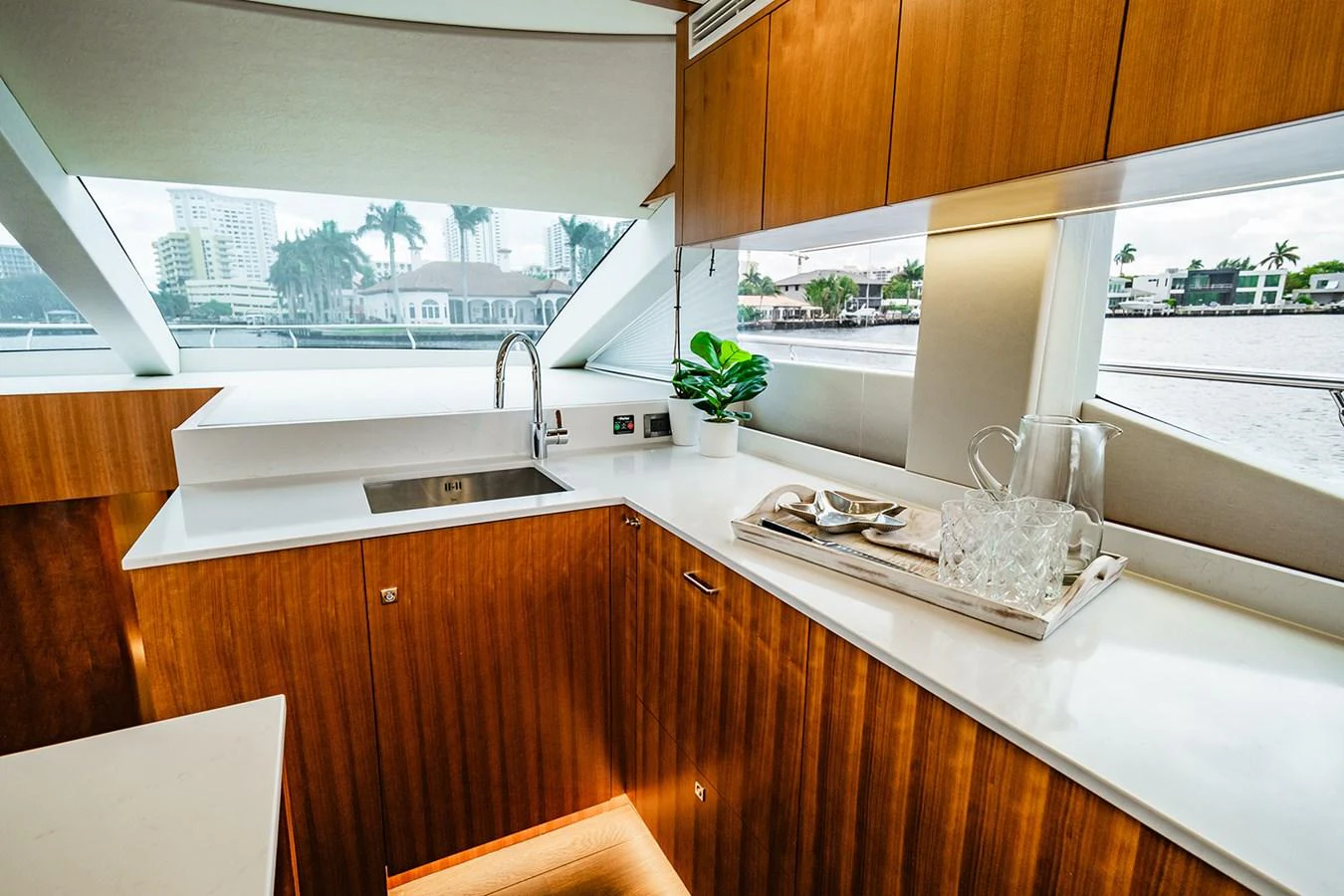 The galley features sleek wooden cabinetry, modern appliances, and large windows offering a scenic view. aboard INDIGO Yacht for Sale